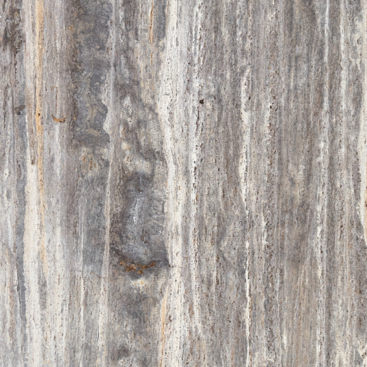 Detalle travertino Plata, poros naturales y vetas lineales en acabado pulido.